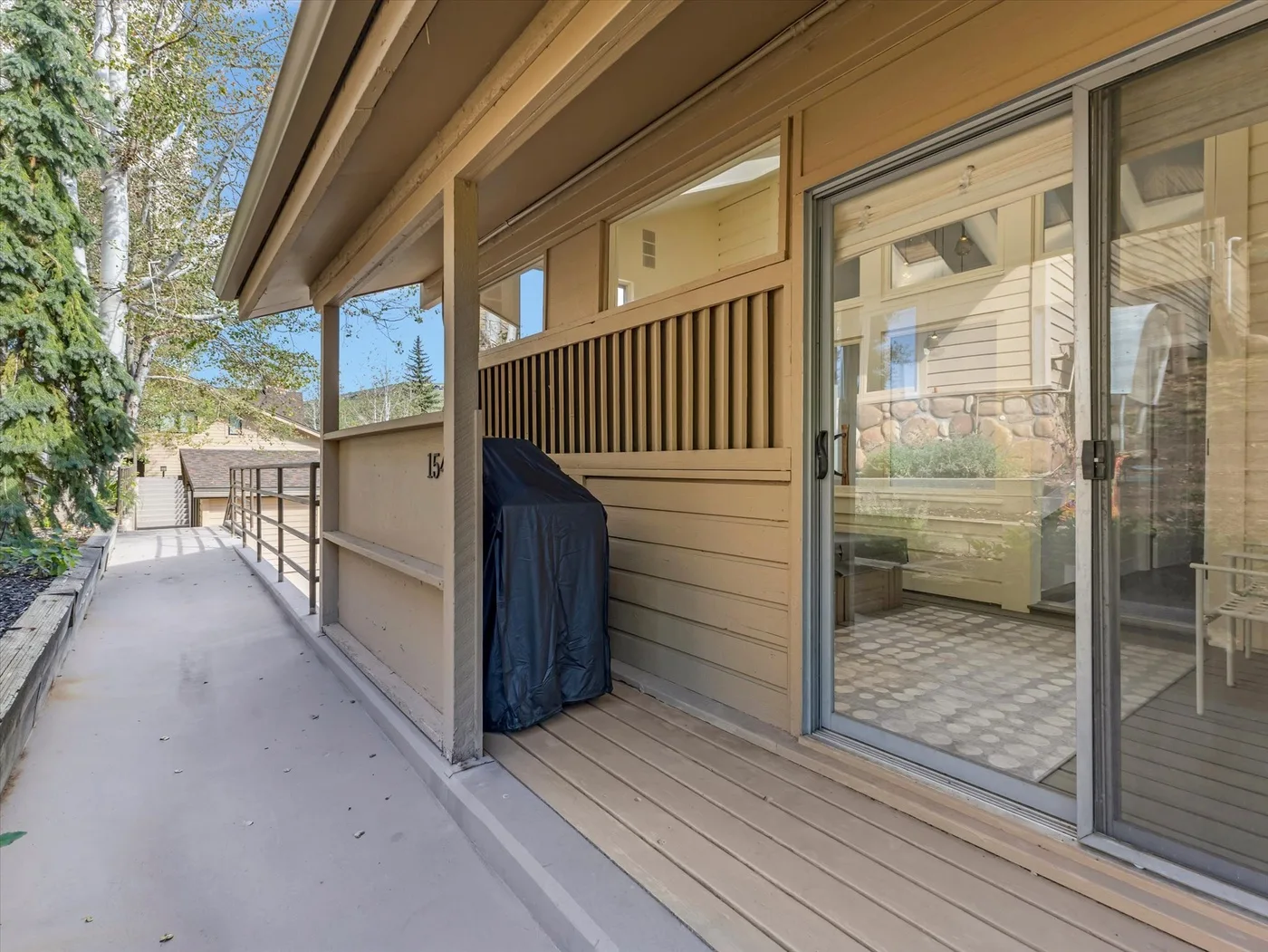 A covered patio walkway runs beside a building with sliding glass doors.