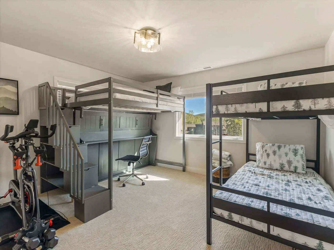 A bedroom with bunk beds, a desk, and exercise equipment.