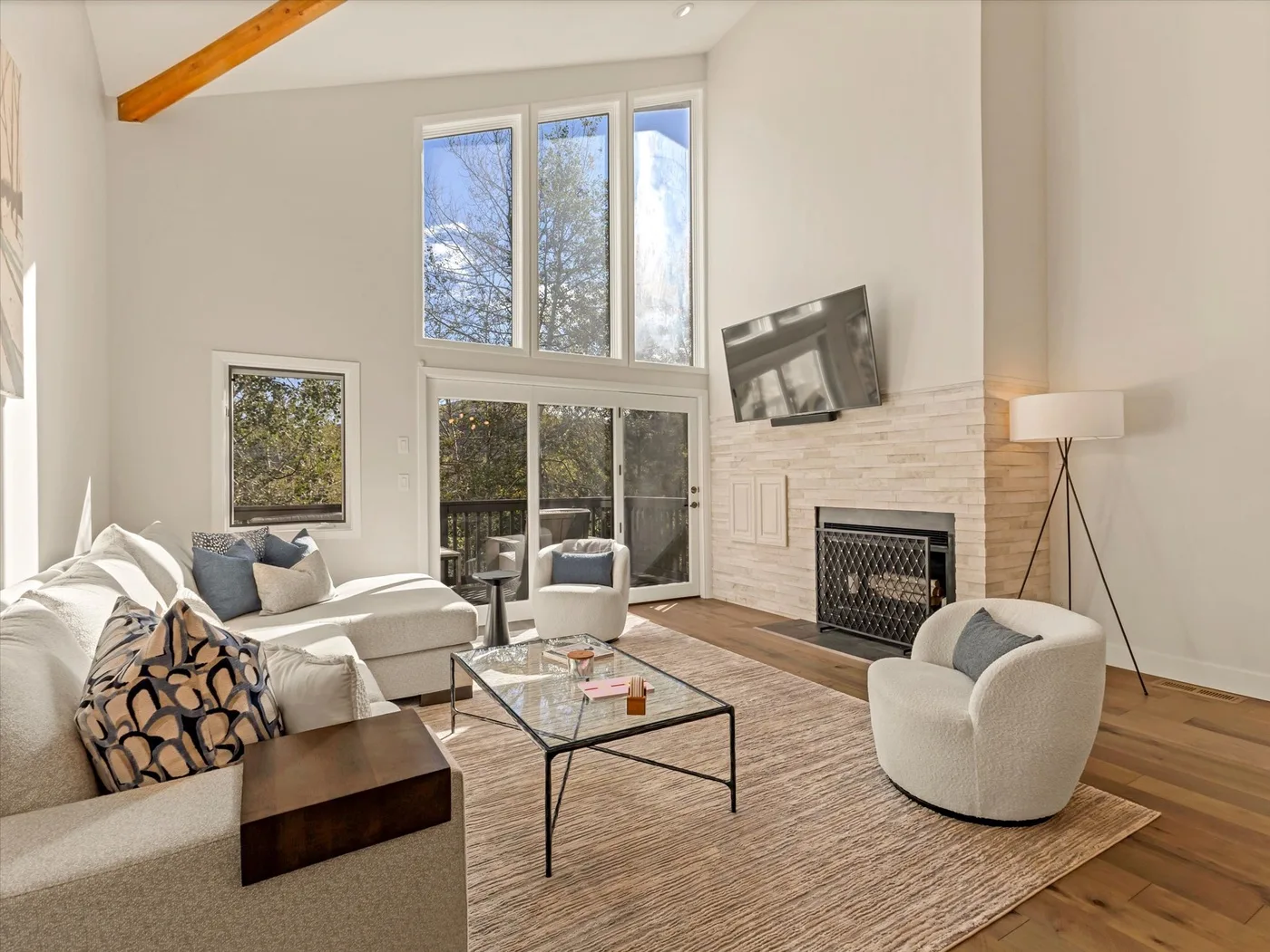 A bright living room with seating, a glass coffee table, and a fireplace.