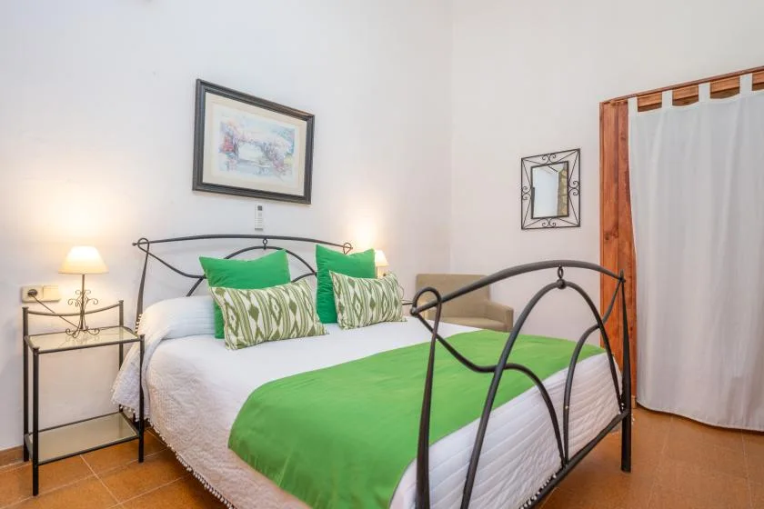 A bedroom with a metal bed, white bedding, and green accents.
