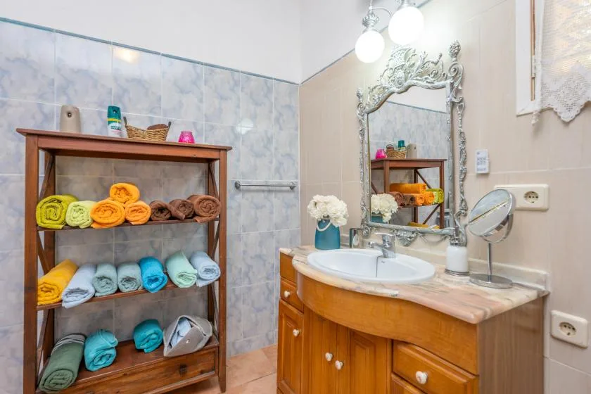 A bathroom vanity with a sink and mirror stands beside shelves of folded towels.