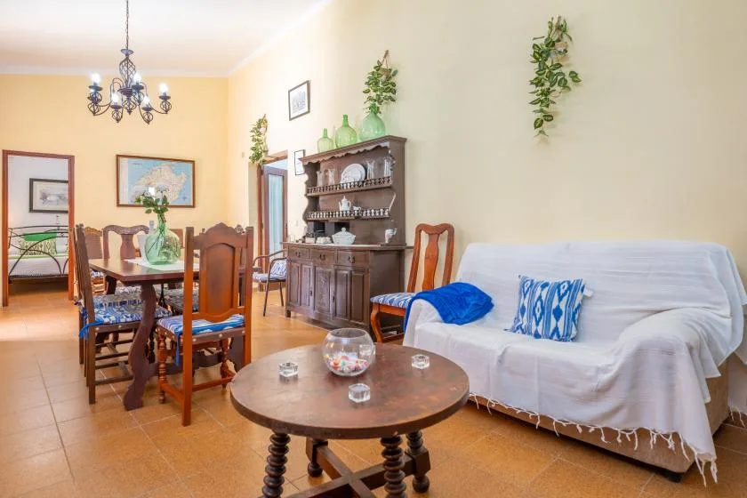 A living and dining room with a white-covered sofa and a wooden dining table.