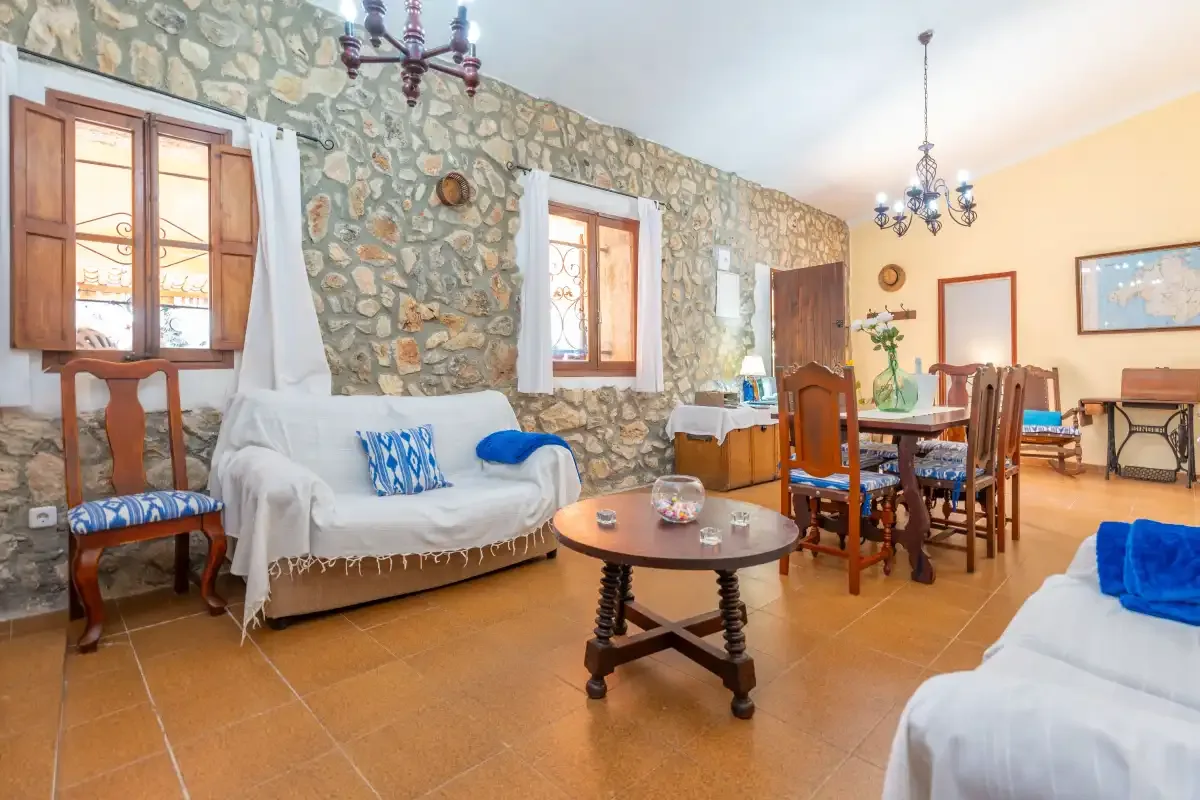 A rustic living and dining room with seating, a wooden table, and stone walls.