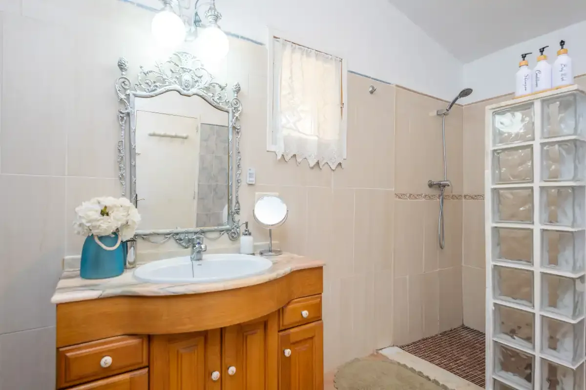 A bathroom with a vanity, mirror, and shower.