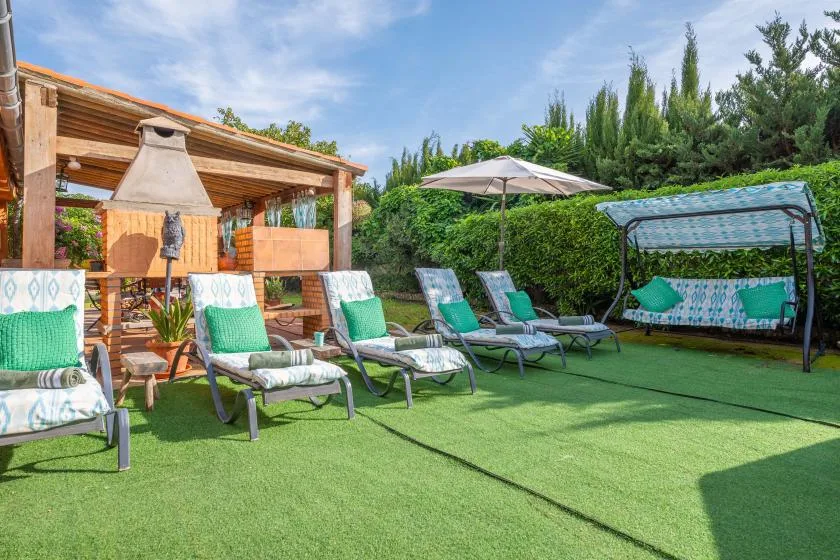 An outdoor patio with lounge seating, a shade umbrella, and a garden swing.