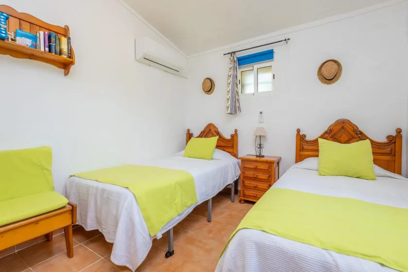 A bright bedroom with wooden beds dressed in white and lime-green bedding.
