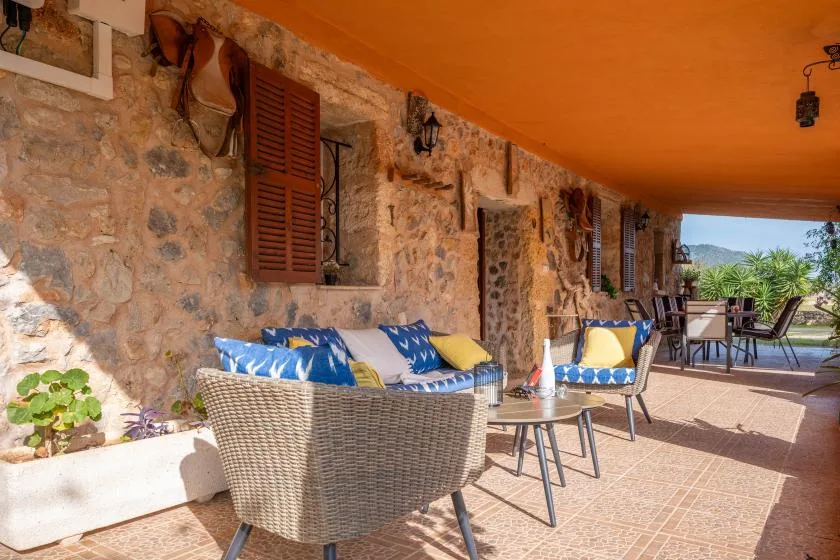 A covered patio with outdoor seating, stone walls, and views of greenery.