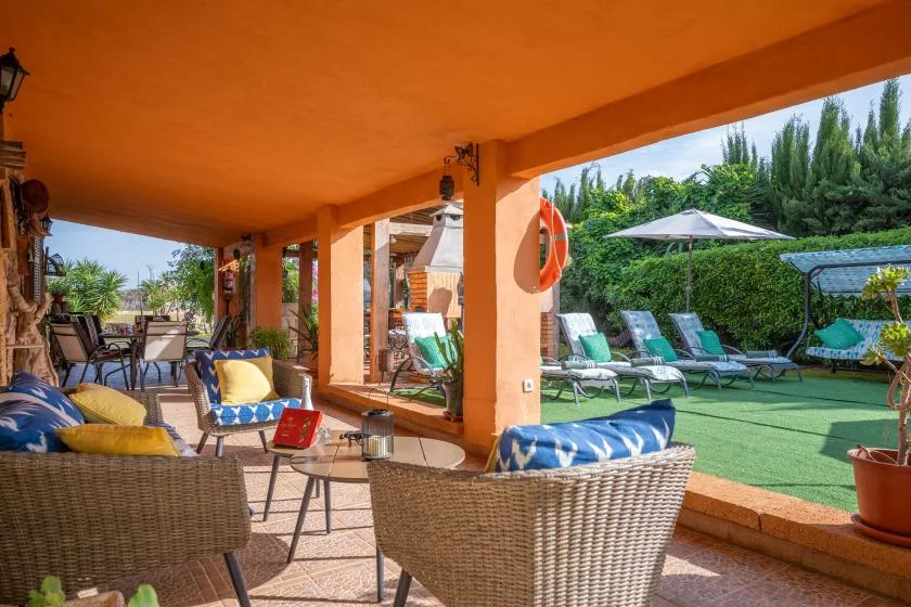 A covered patio with outdoor seating overlooks a garden lounge area.