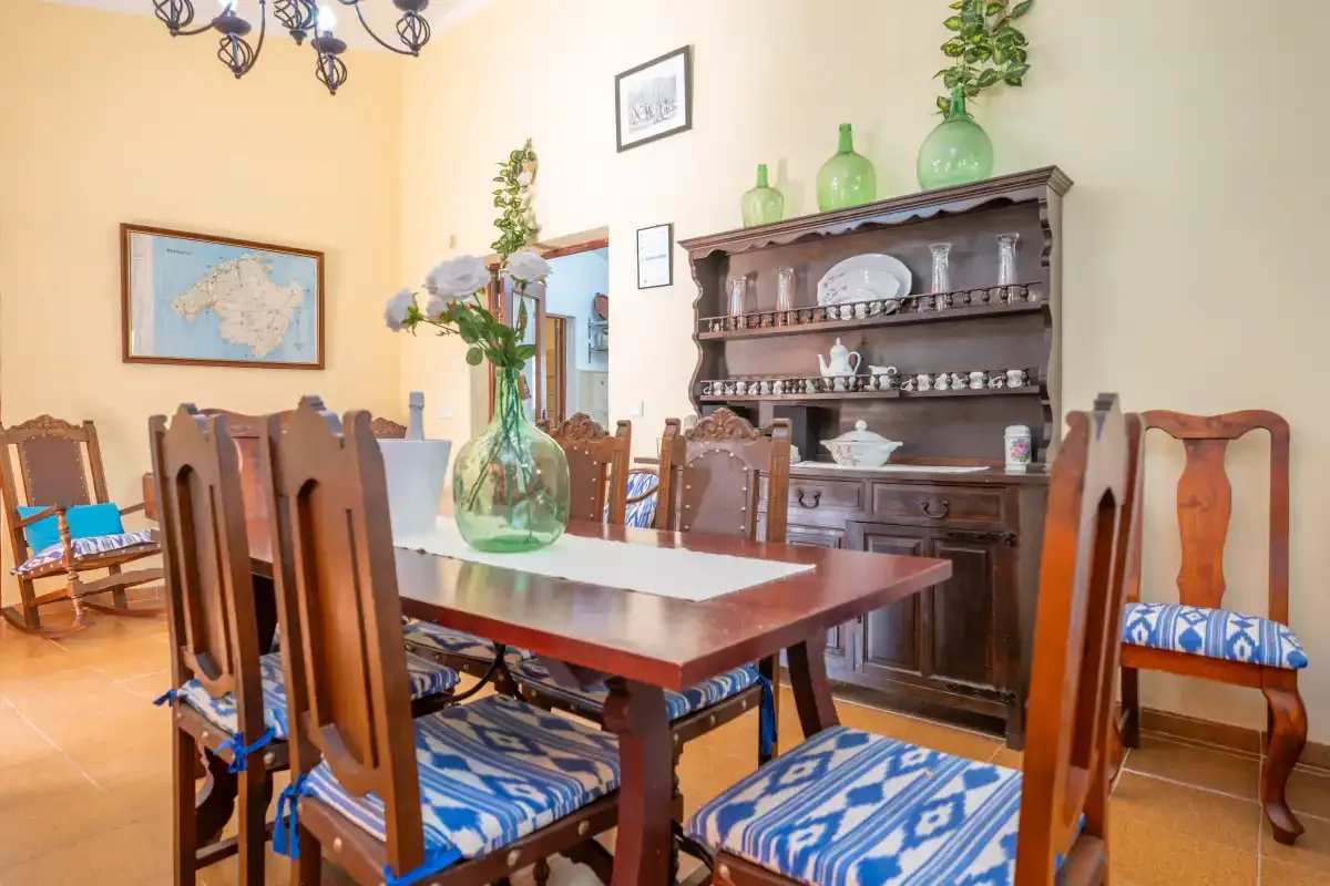 A dining room with a long wooden table and a display cabinet.