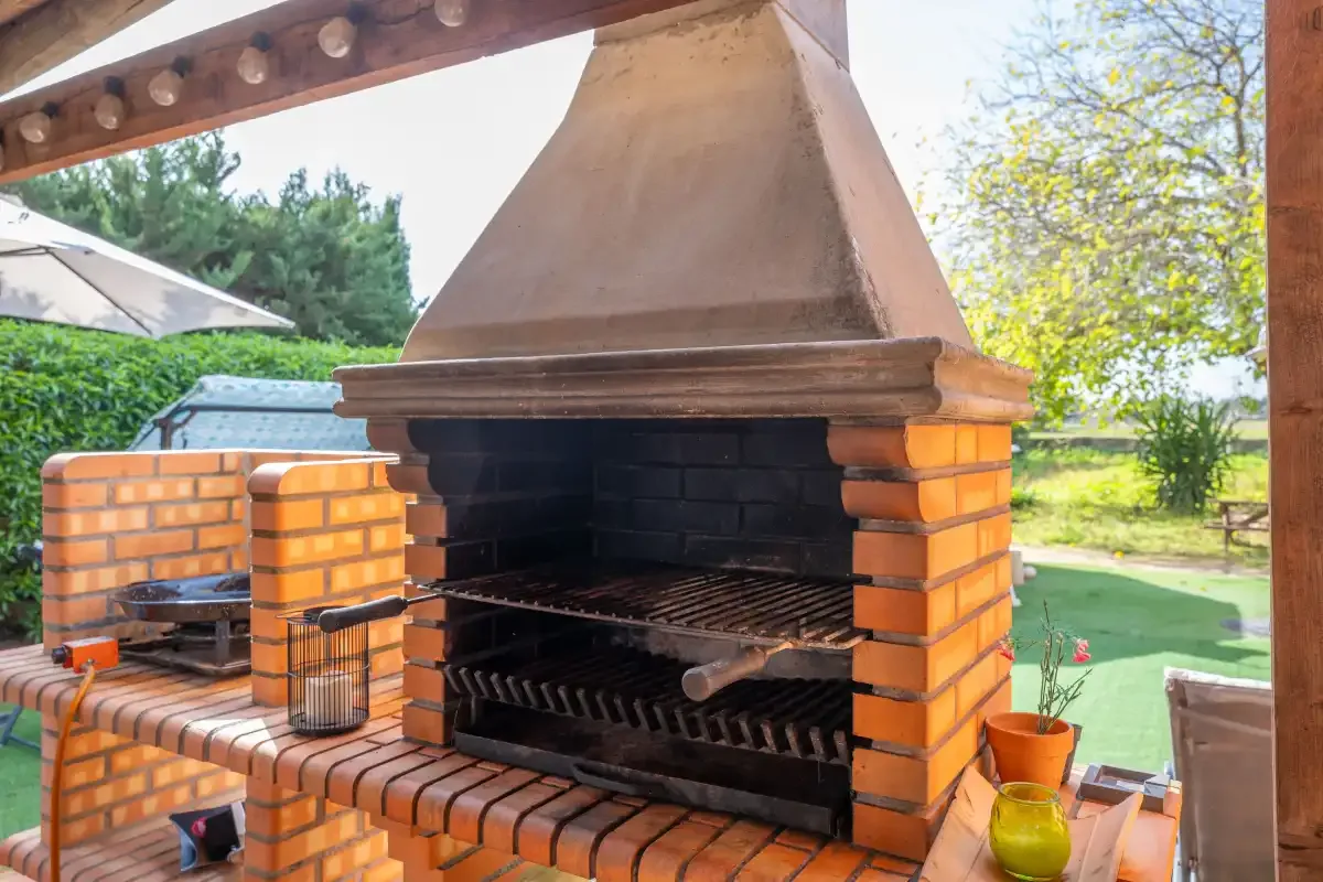An outdoor brick barbecue grill beneath a covered patio.