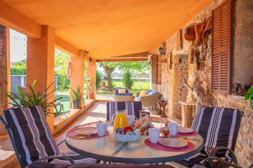 A covered outdoor terrace with a dining table, lounge seating, and garden views.