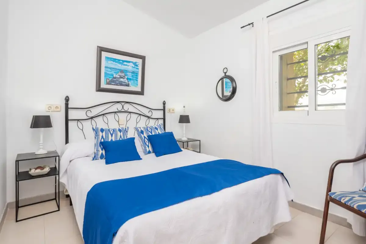 A bedroom with a double bed dressed in white and blue bedding.