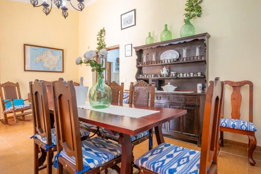 A dining room with a wooden table, matching chairs, and a display cabinet.