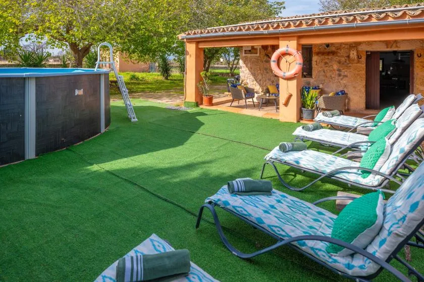 An outdoor poolside area with lounge chairs on a green lawn.