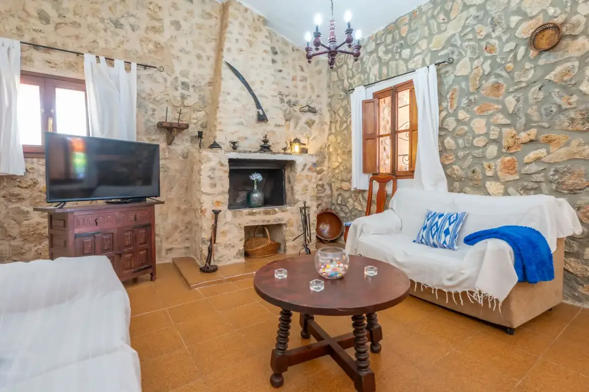 A stone-walled living room with a fireplace, television, and seating.