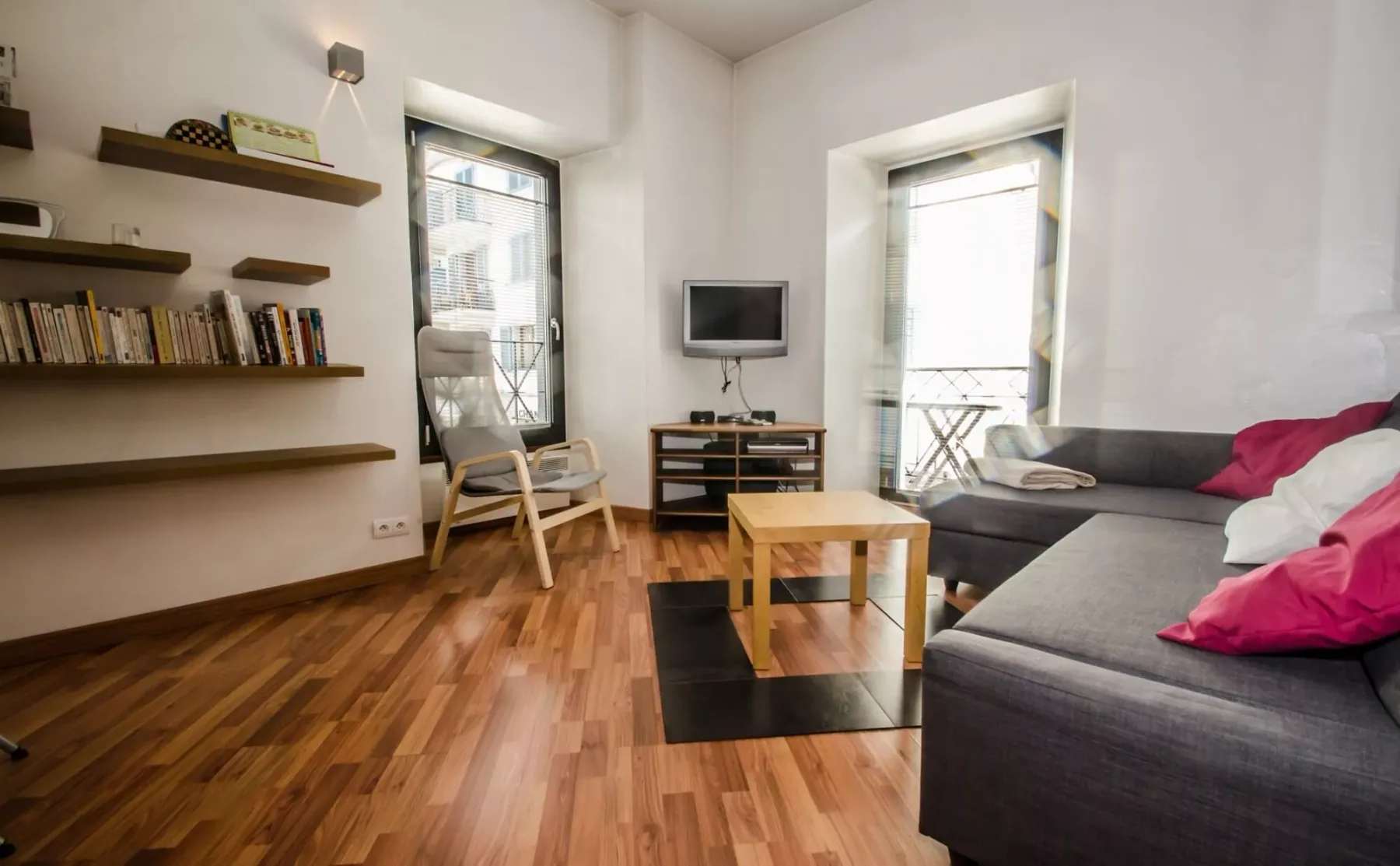 Una sala de estar con asientos, una mesa de centro y ventanas altas.