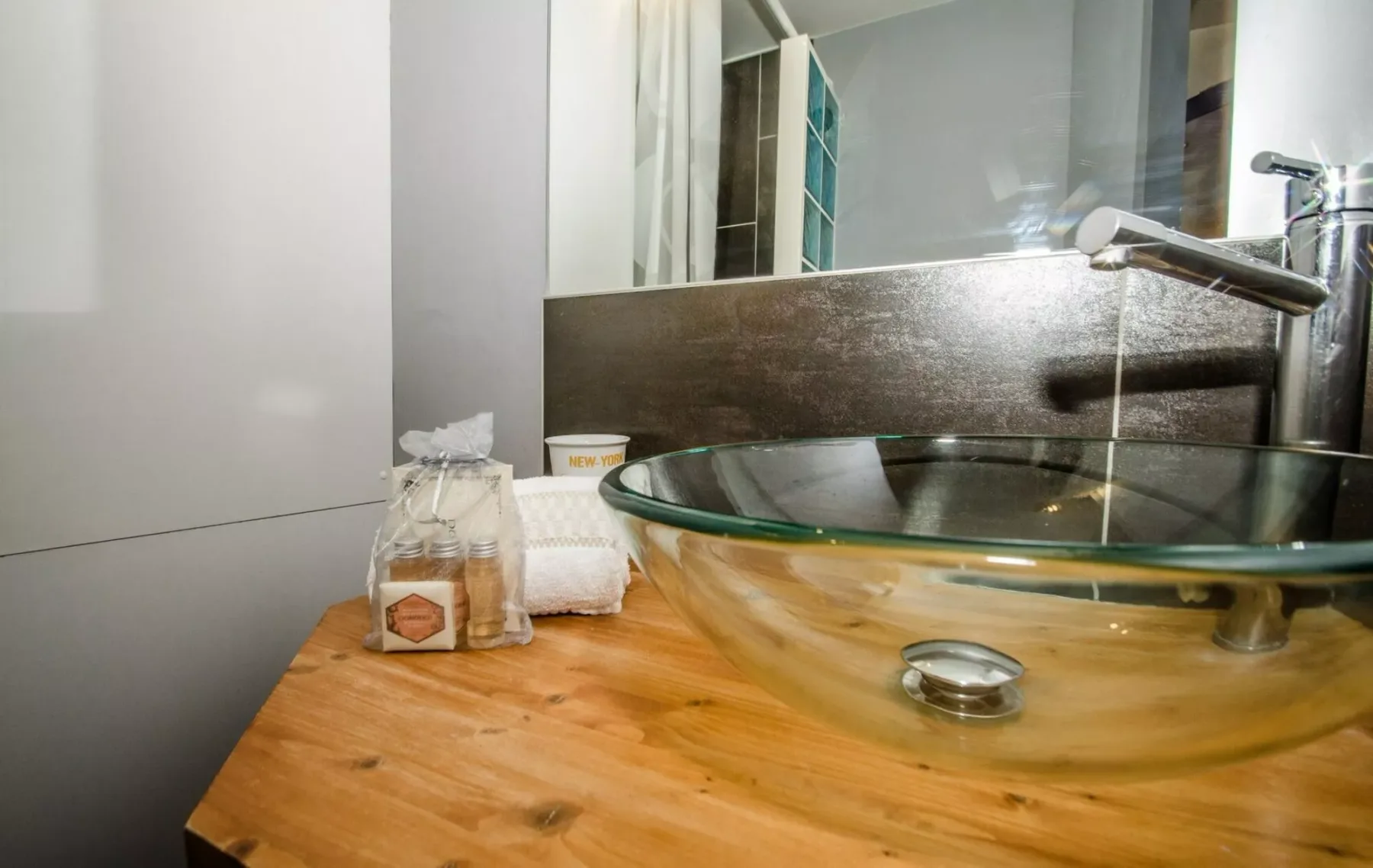 Un lavabo de baño con un lavamanos de vidrio y un espejo.