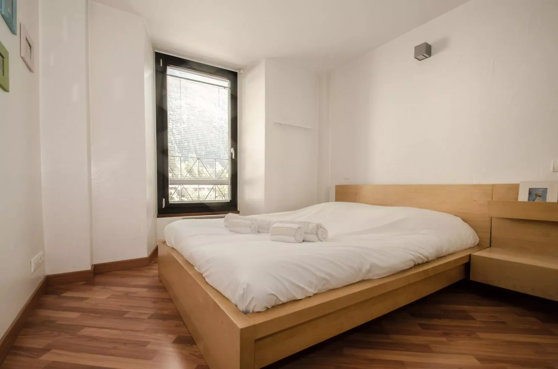 A bright bedroom with a low bed beside a window.
