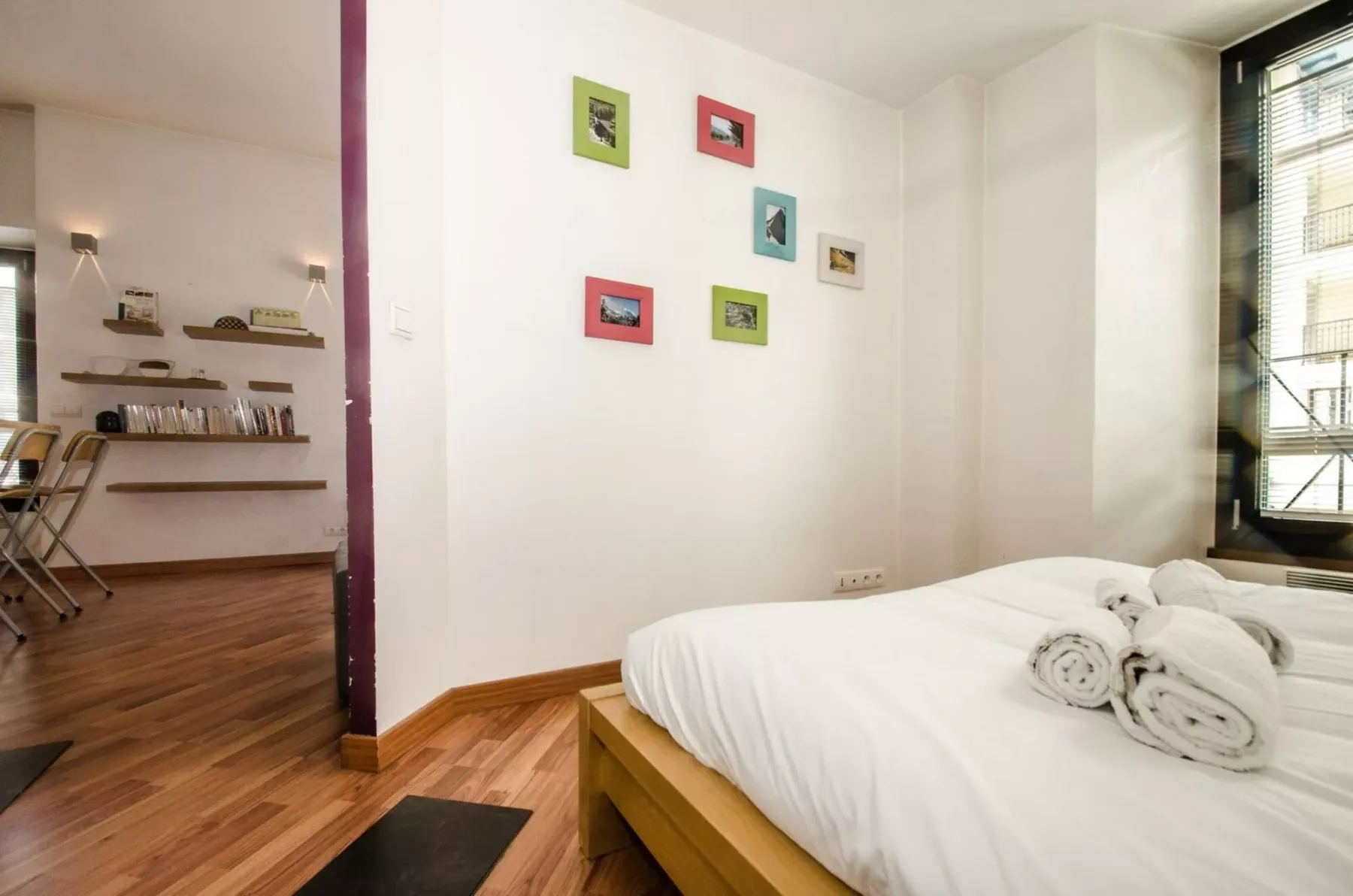 A bedroom with a neatly made bed and small framed pictures on the wall.