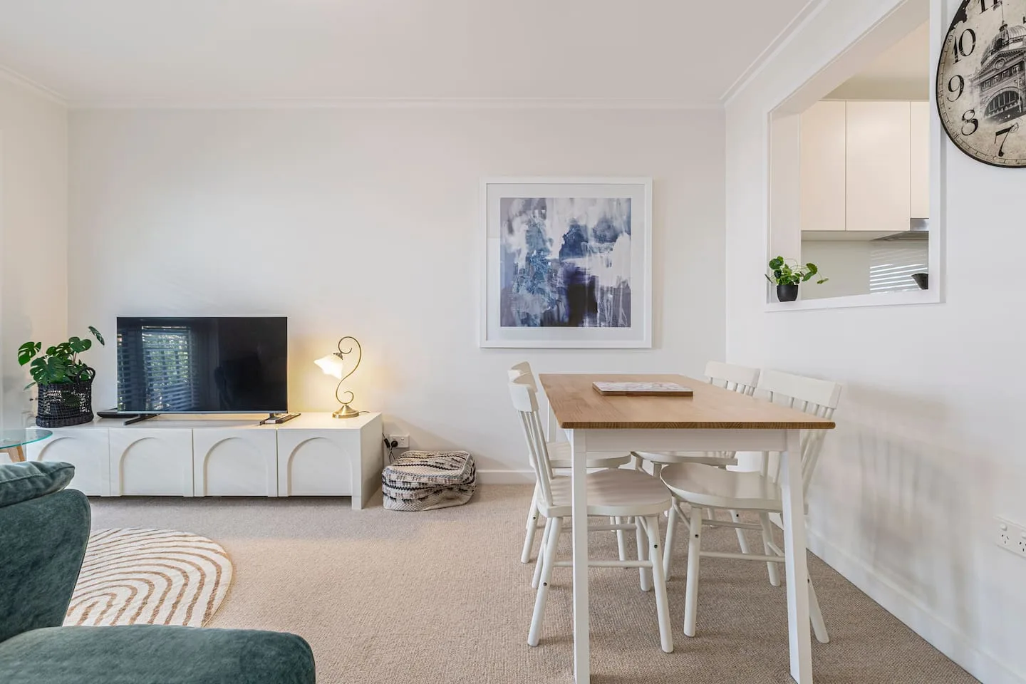 A bright living and dining area with a television and a wooden dining table.