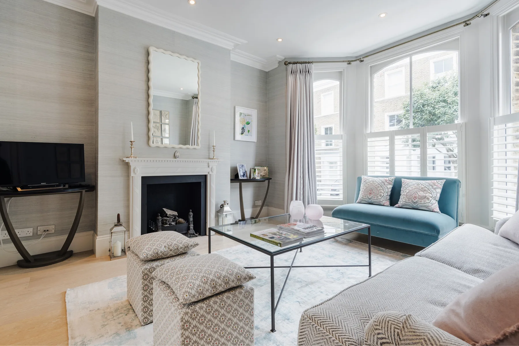 A bright living room with large windows, a fireplace, and seating around a coffee table.