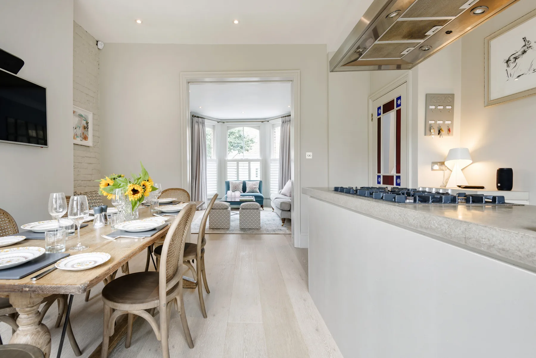 A bright dining area opens onto a living room with large windows.