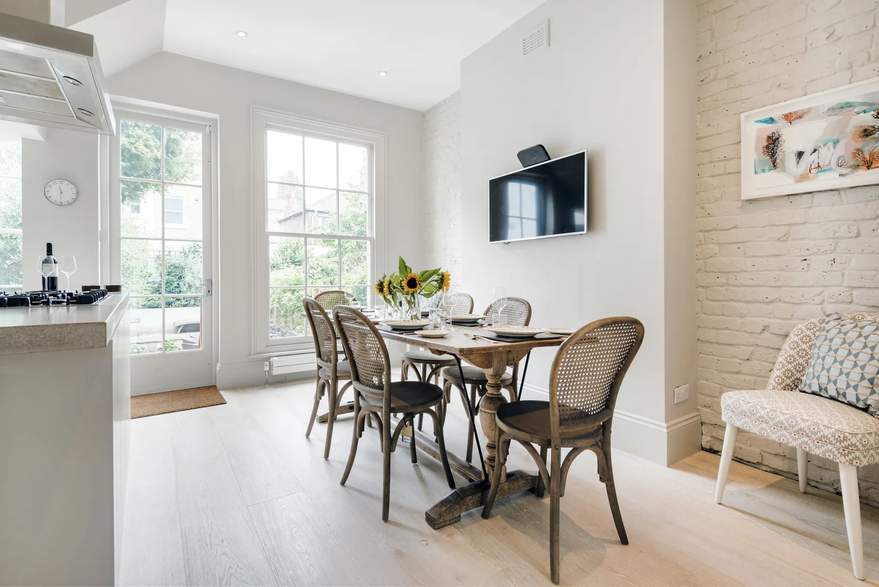 A bright dining area with a table and chairs beside large windows.