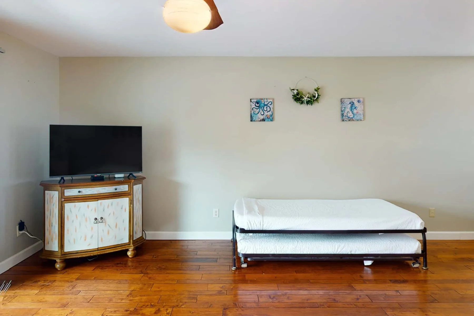 A bedroom with a bed, television, and wooden cabinet against the wall.