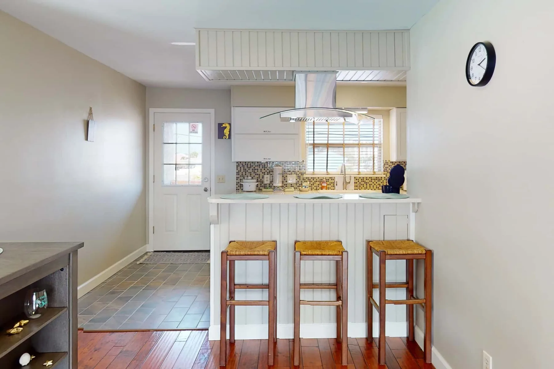 A bright kitchen with a breakfast counter and wooden seating.