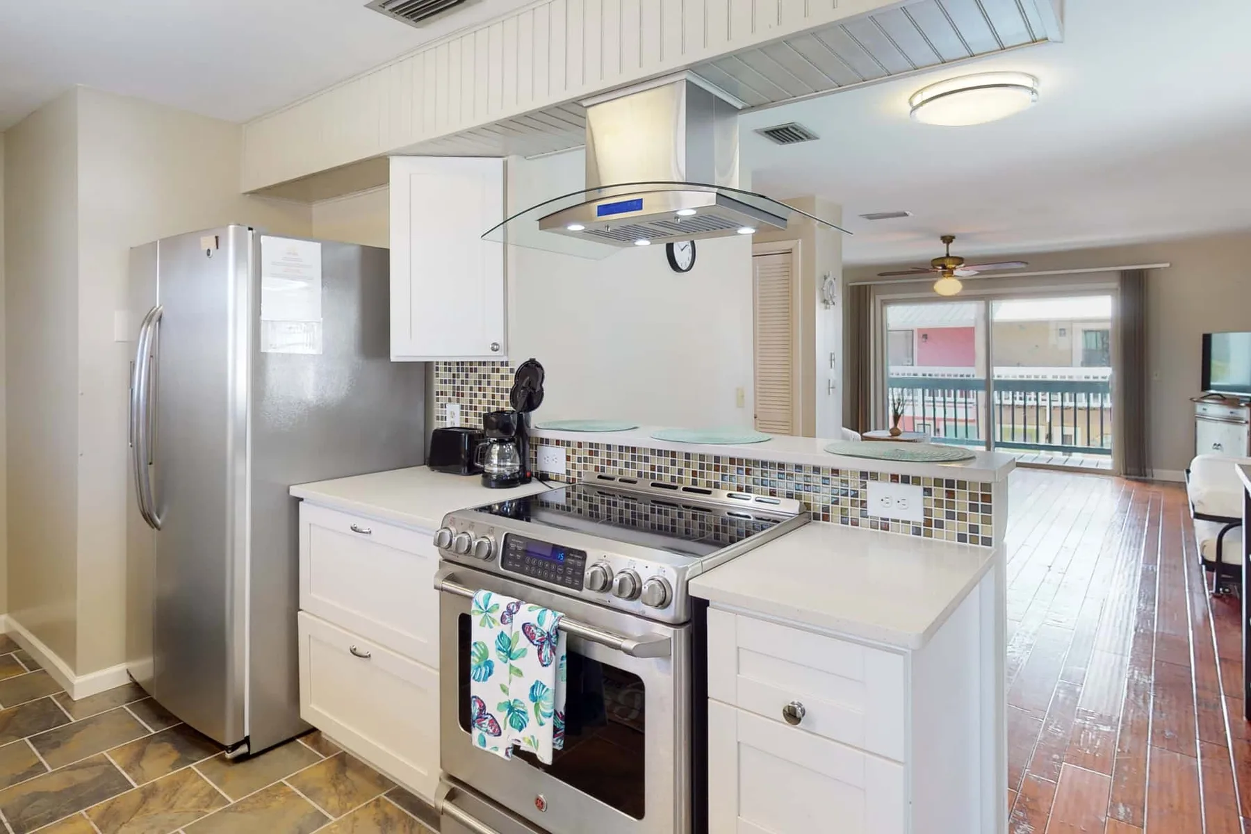A bright kitchen with white cabinetry opens onto a dining area and balcony.