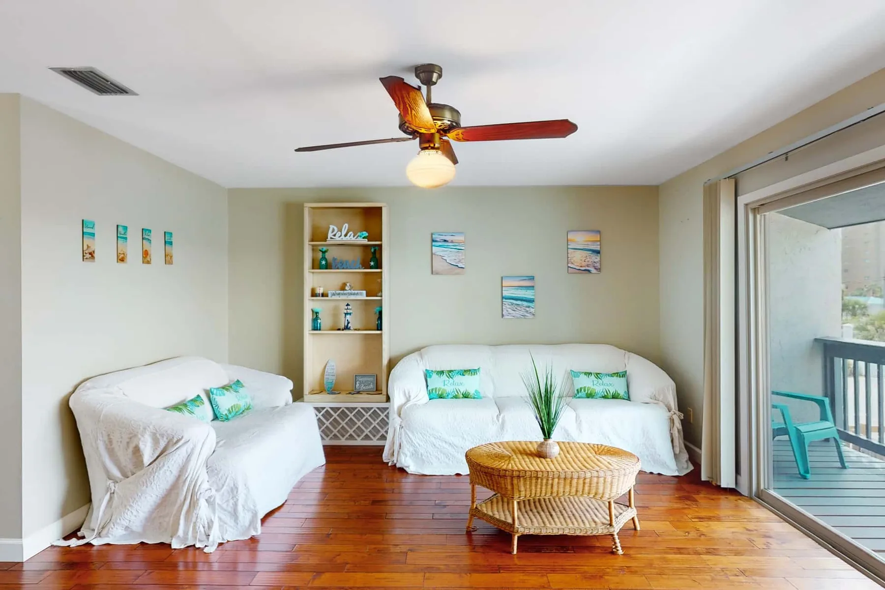 A bright living room with white-covered seating and a wicker coffee table.