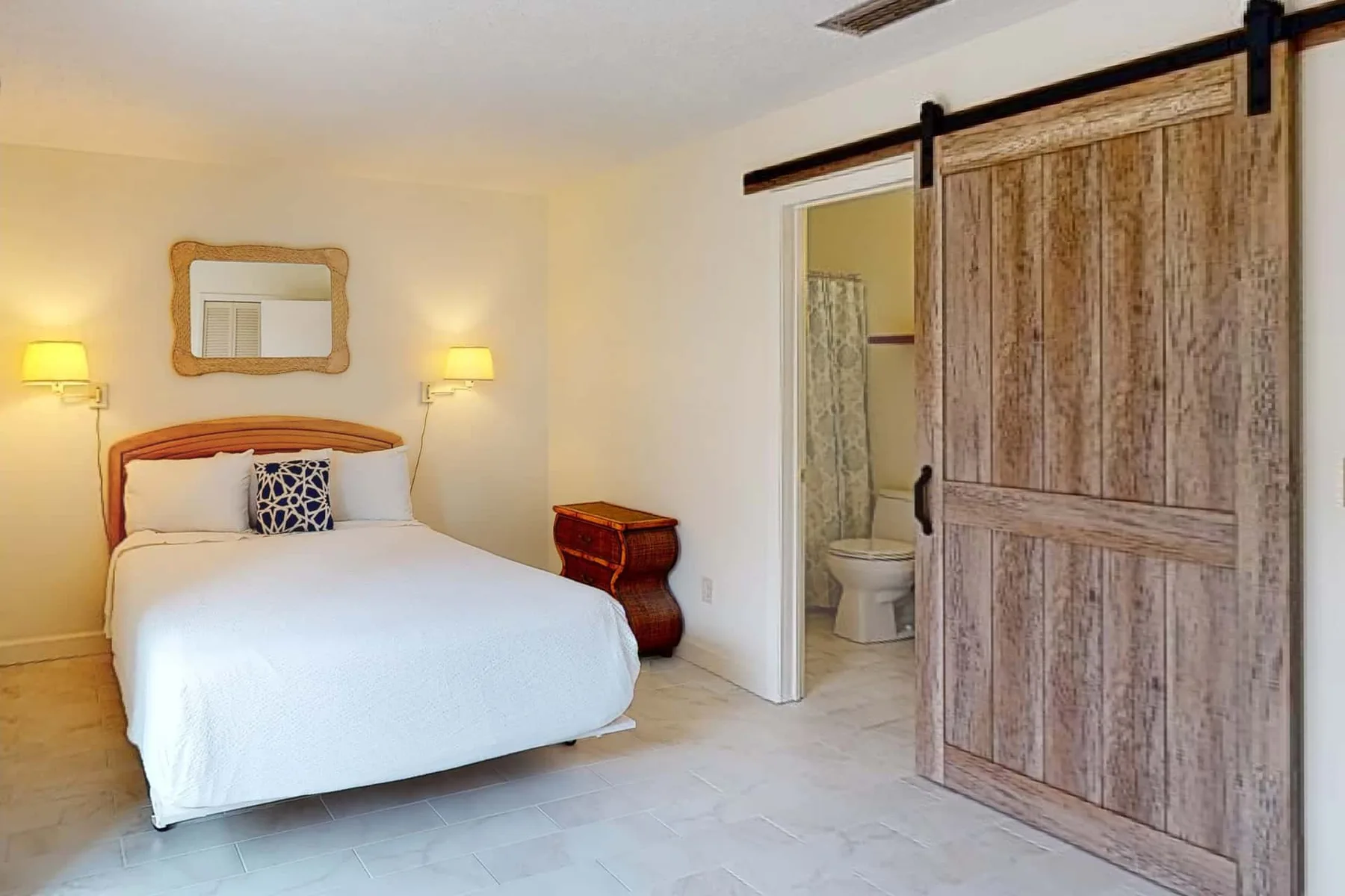 A bedroom with a bed and a sliding wooden door opening onto a bathroom.