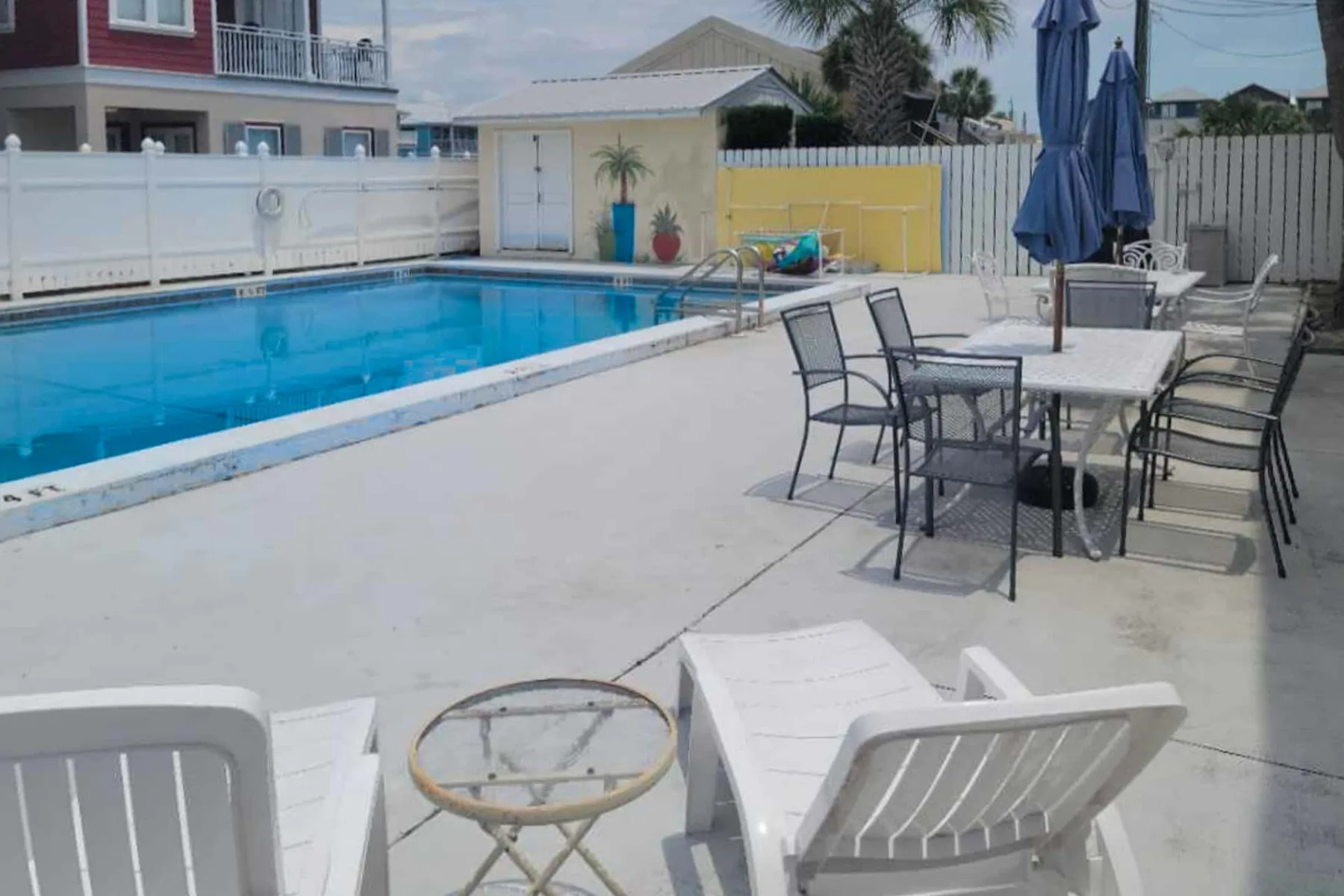 An outdoor poolside patio with lounge seating and a dining table.
