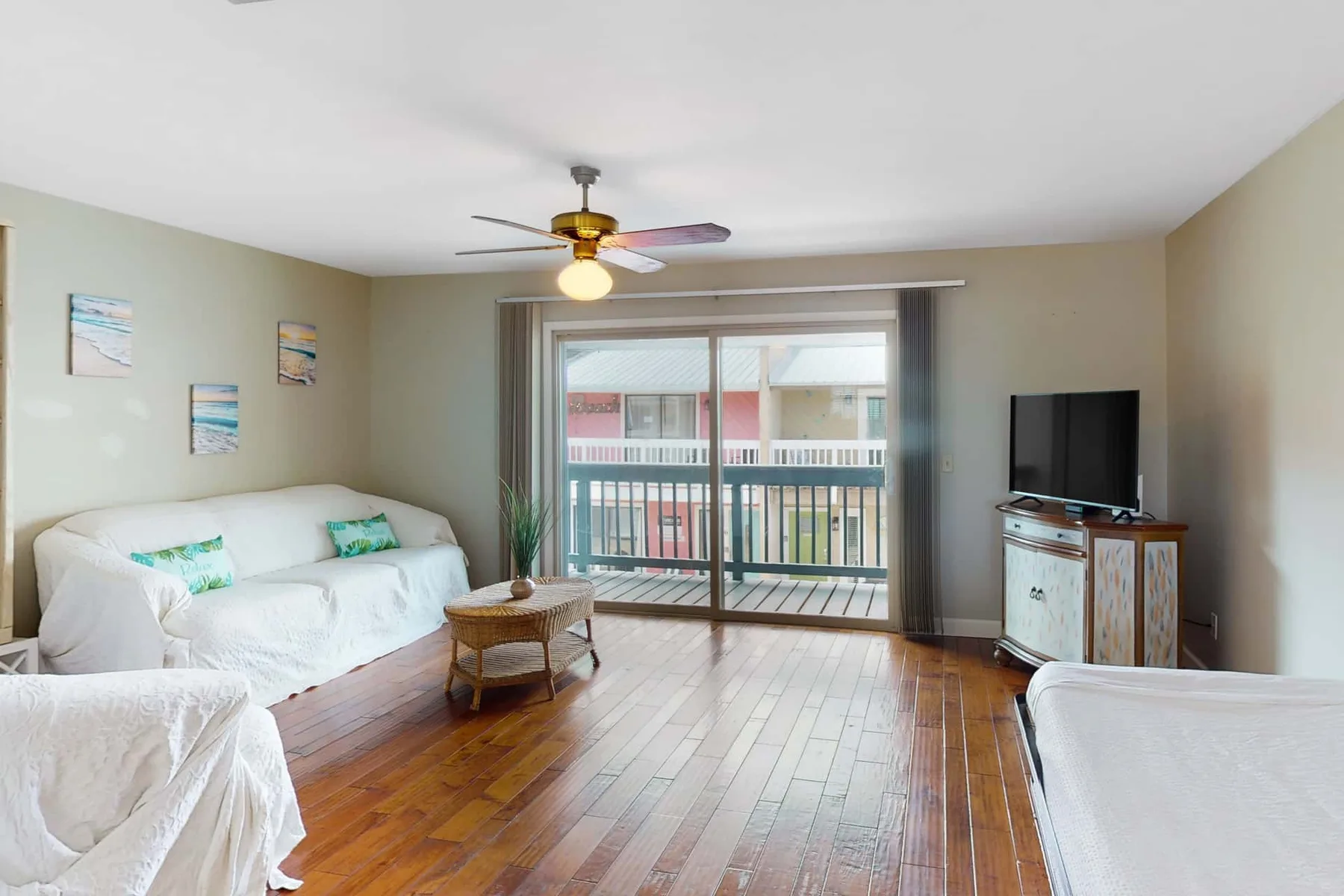 A living room with seating, a television, and sliding glass doors opening onto a balcony.