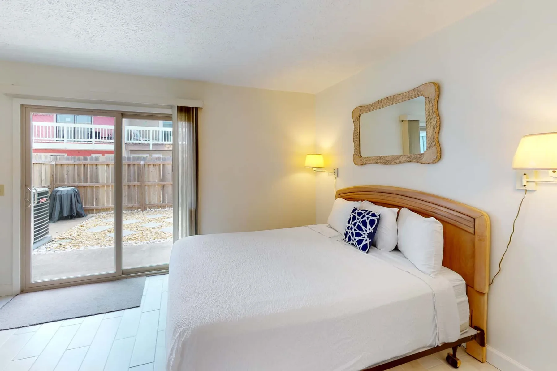 A bedroom with a neatly made bed and sliding glass doors opening to a patio.