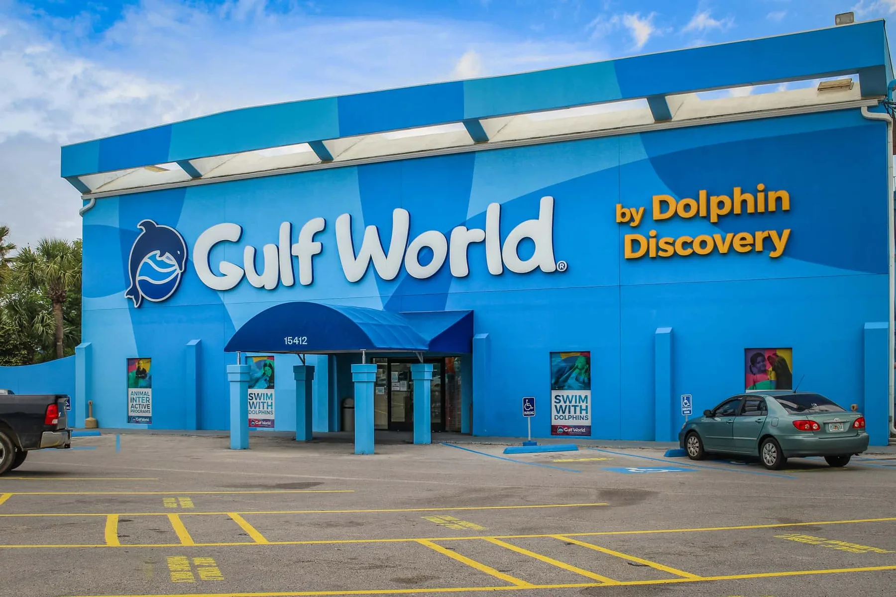 A bright blue Gulf World building faces a parking lot under a partly cloudy sky.