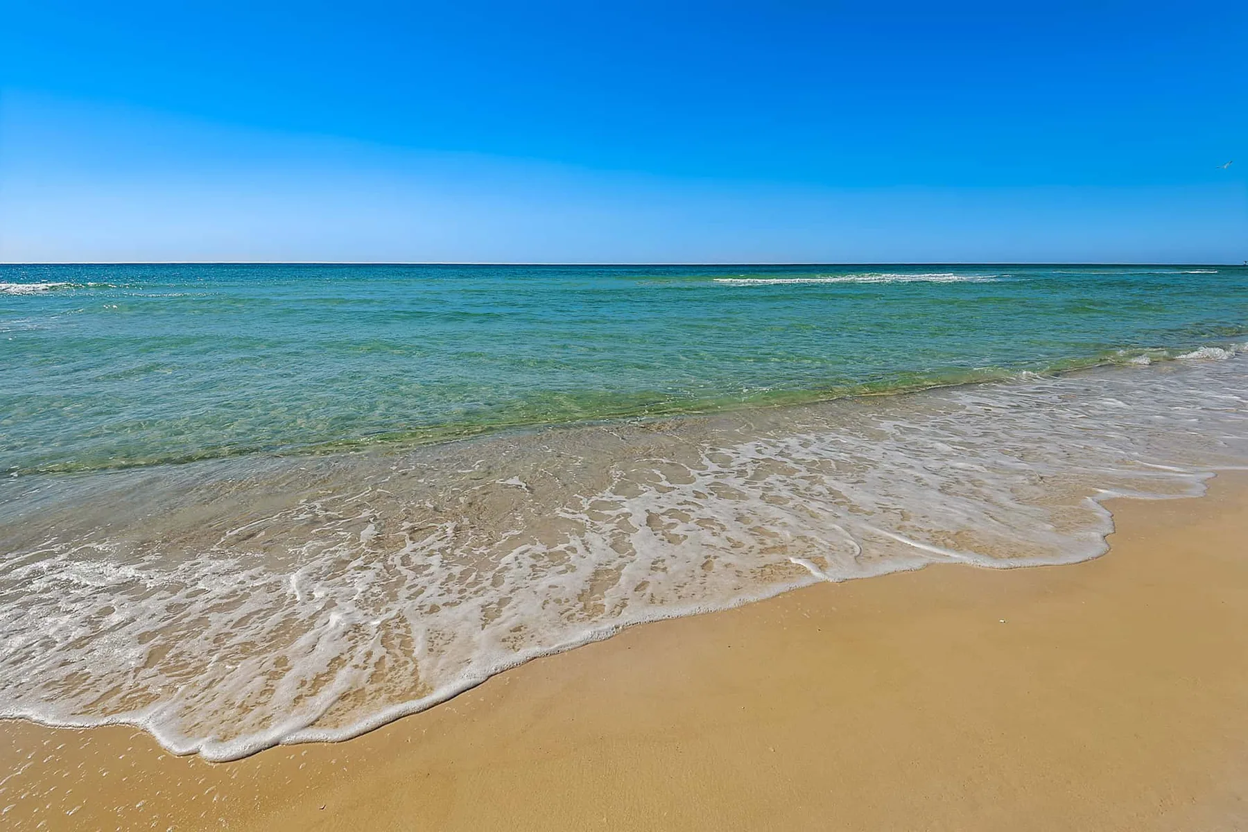 A sandy beach with gentle waves rolling onto the shore.