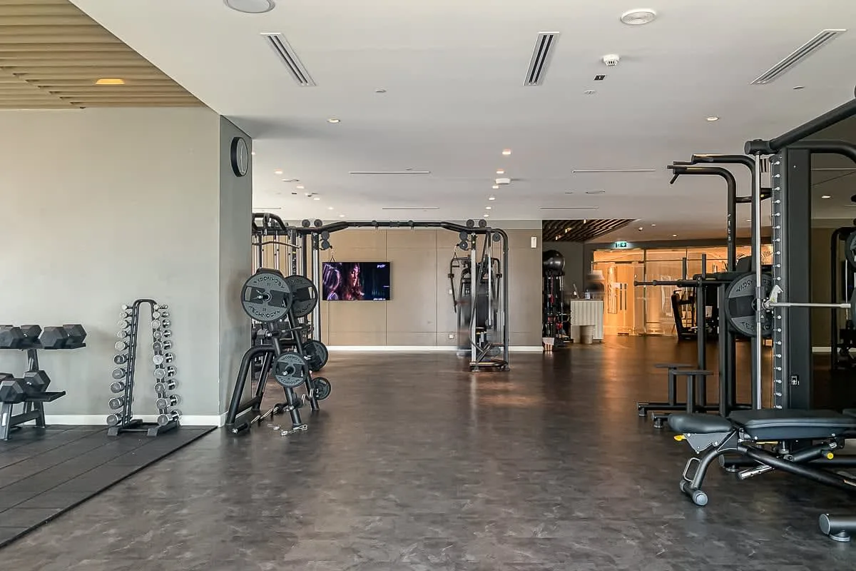 Un gimnasio con máquinas de ejercicio y pesas distribuidas por el espacio.
