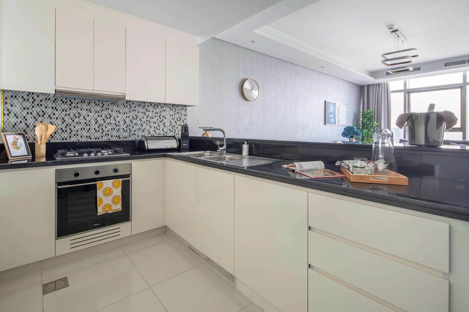Una cocina moderna y luminosa con gabinetes blancos, encimeras oscuras y un salpicadero estampado.