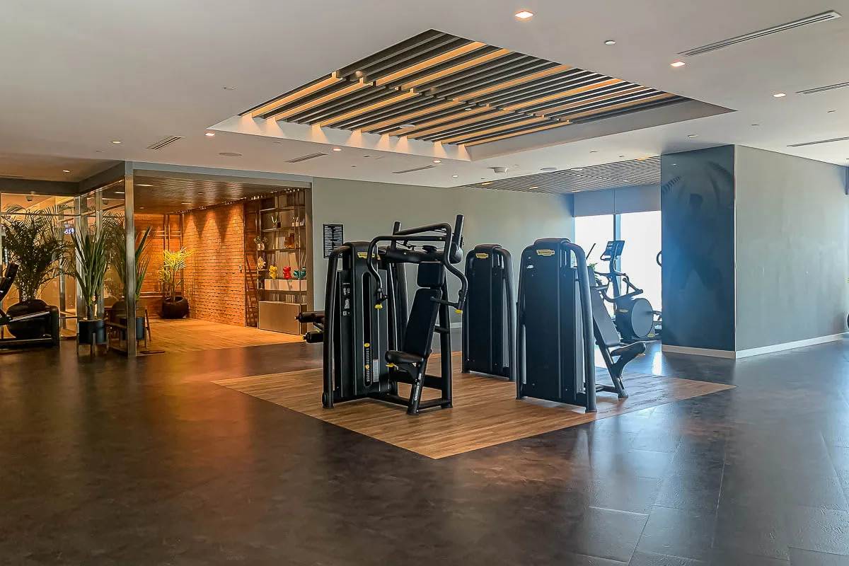 Zona de gimnasio con máquinas de ejercicio sobre una plataforma de suelo de madera.