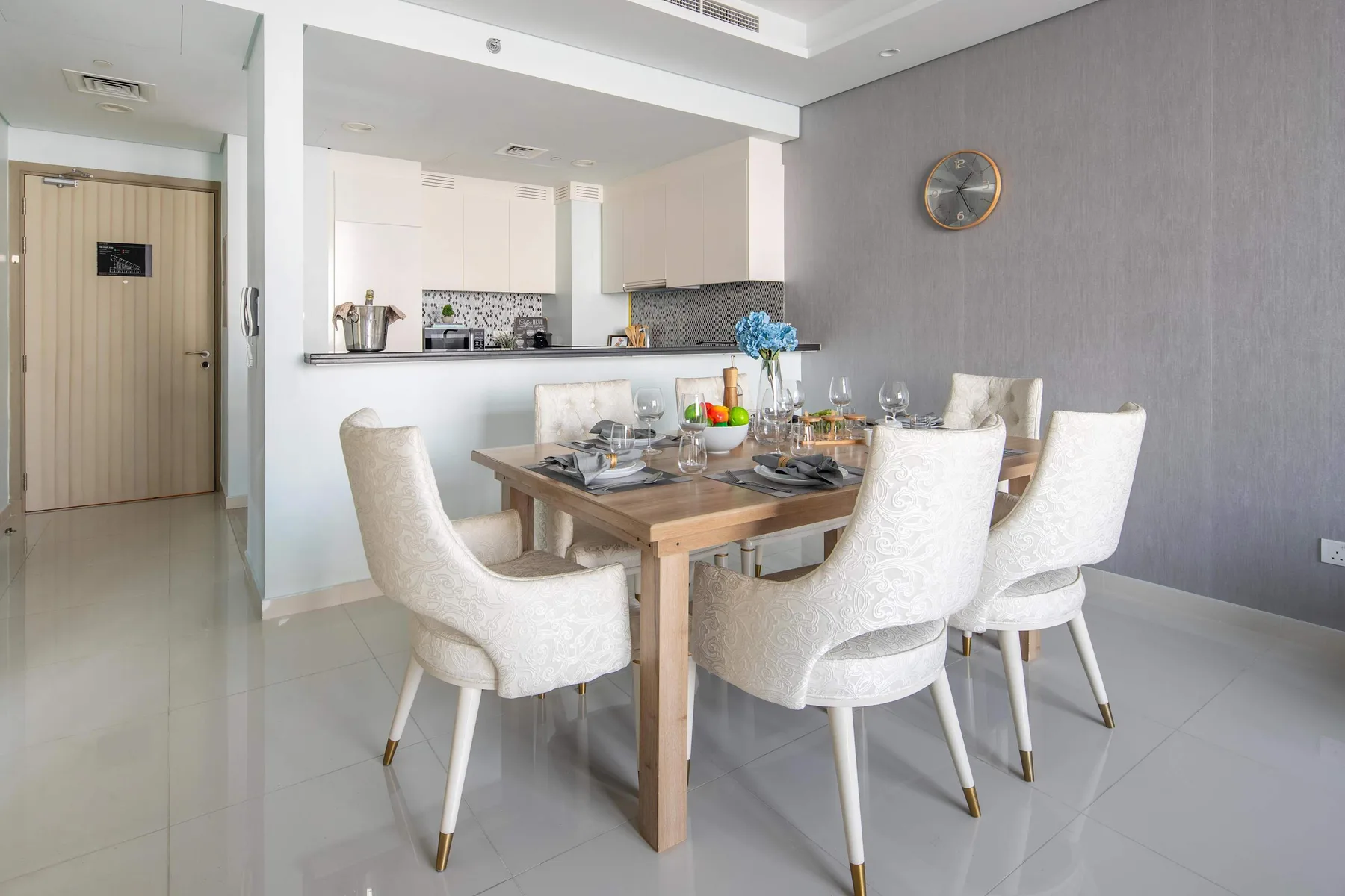 Un comedor con una mesa de madera puesta con platos junto a una cocina abierta.