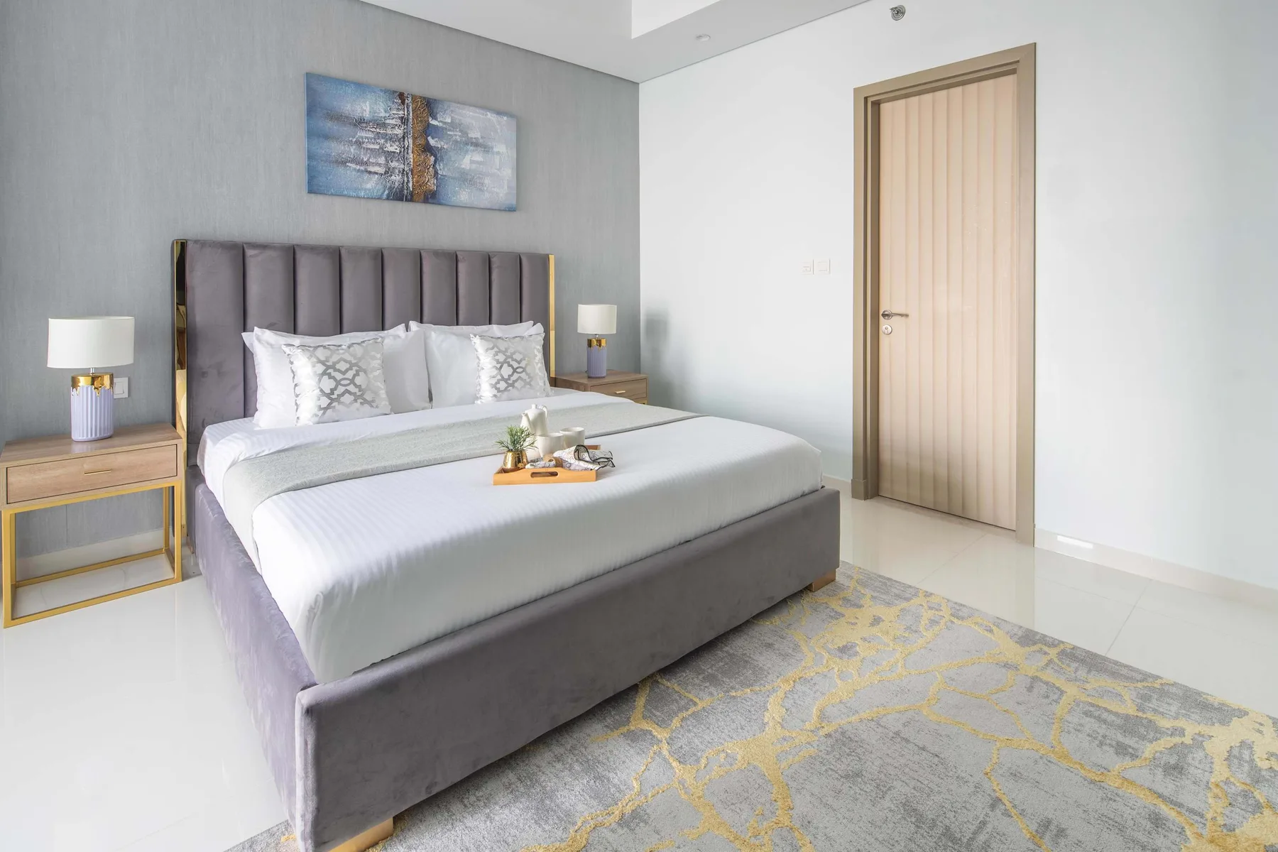 Un dormitorio con una cama bien hecha, mesitas de noche y una alfombra estampada.