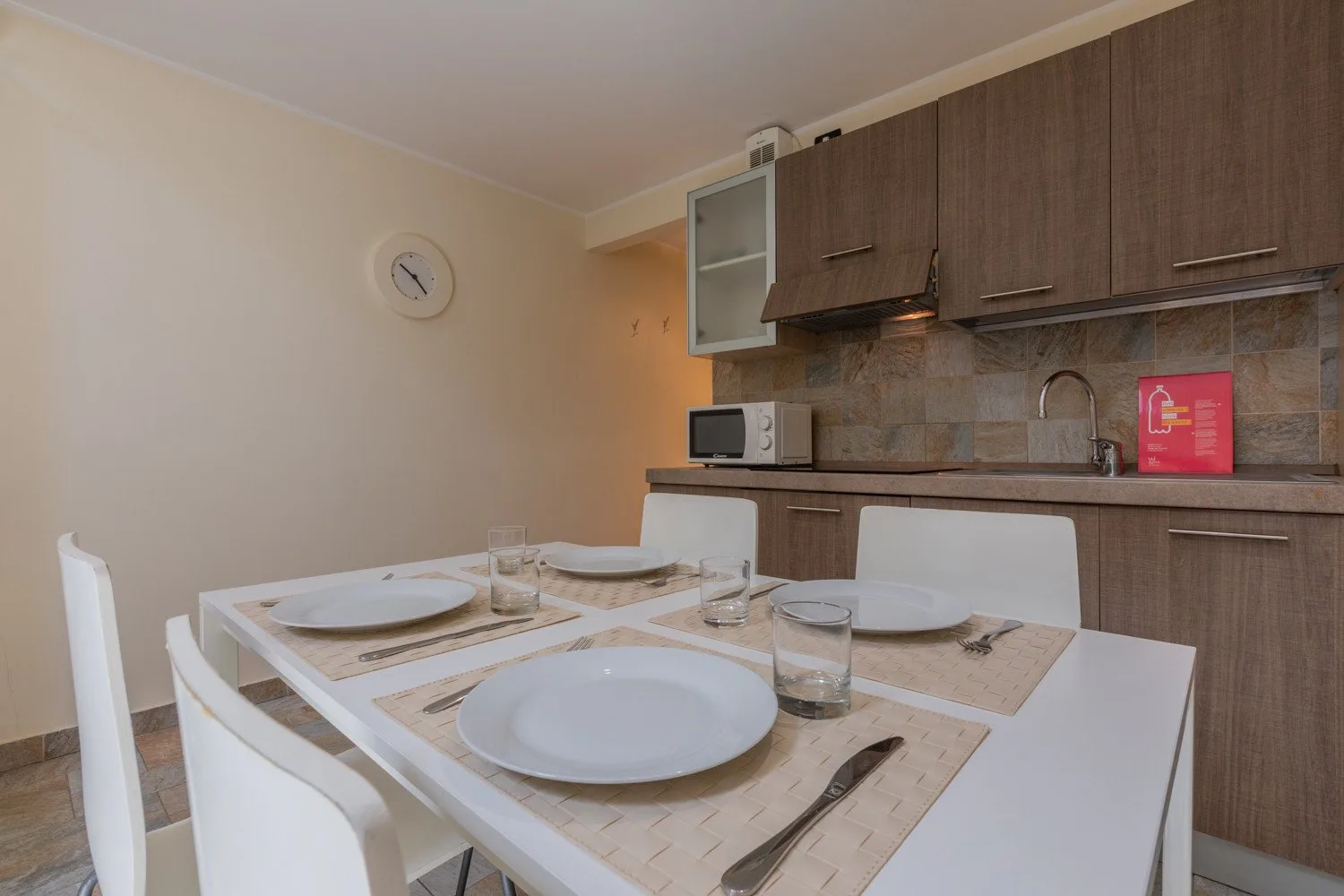 Un comedor con la mesa puesta junto a los armarios de la cocina.