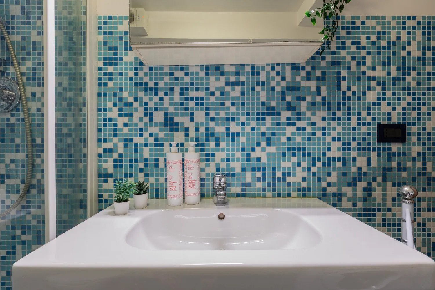 Un lavabo de baño blanco frente a azulejos de mosaico azul.