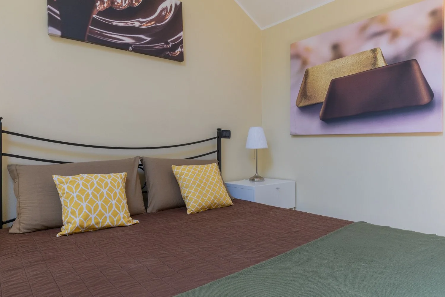 Un dormitorio con una cama vestida con ropa de cama marrón y verde.
