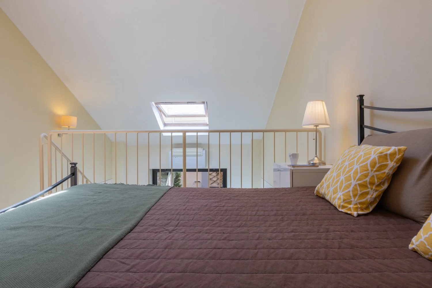 Un dormitorio abuhardillado con una cama bajo un techo inclinado y una claraboya.
