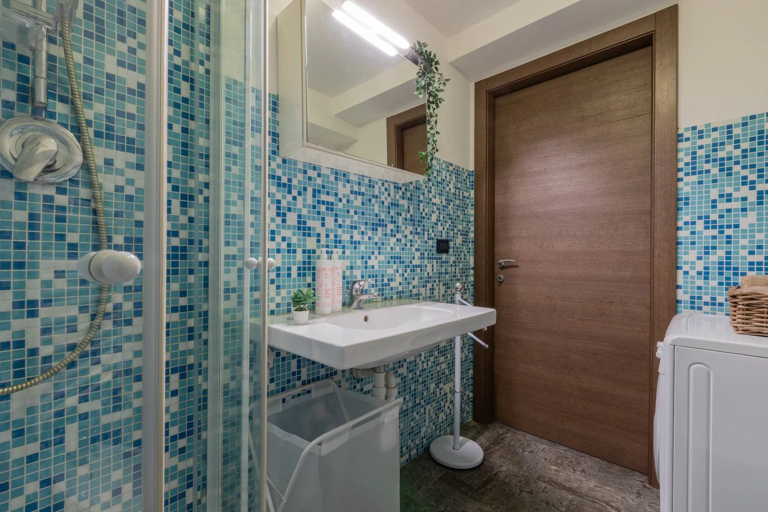 Un baño con azulejos, lavabo, espejo, ducha y puerta de madera.
