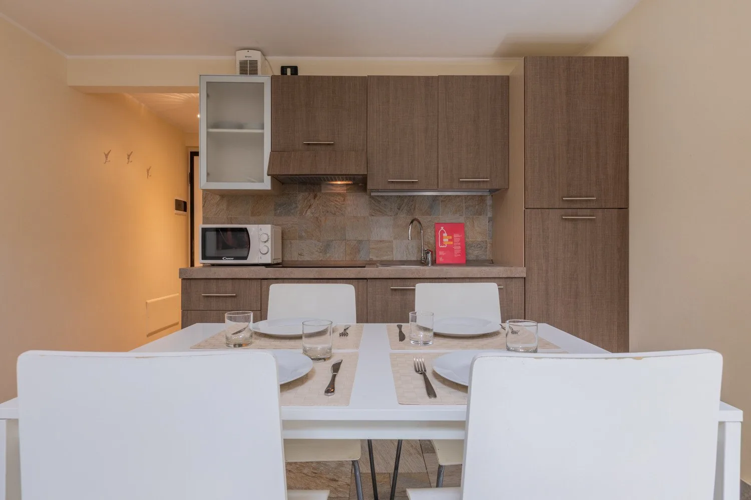 Comedor con una mesa puesta y la cocina al fondo.