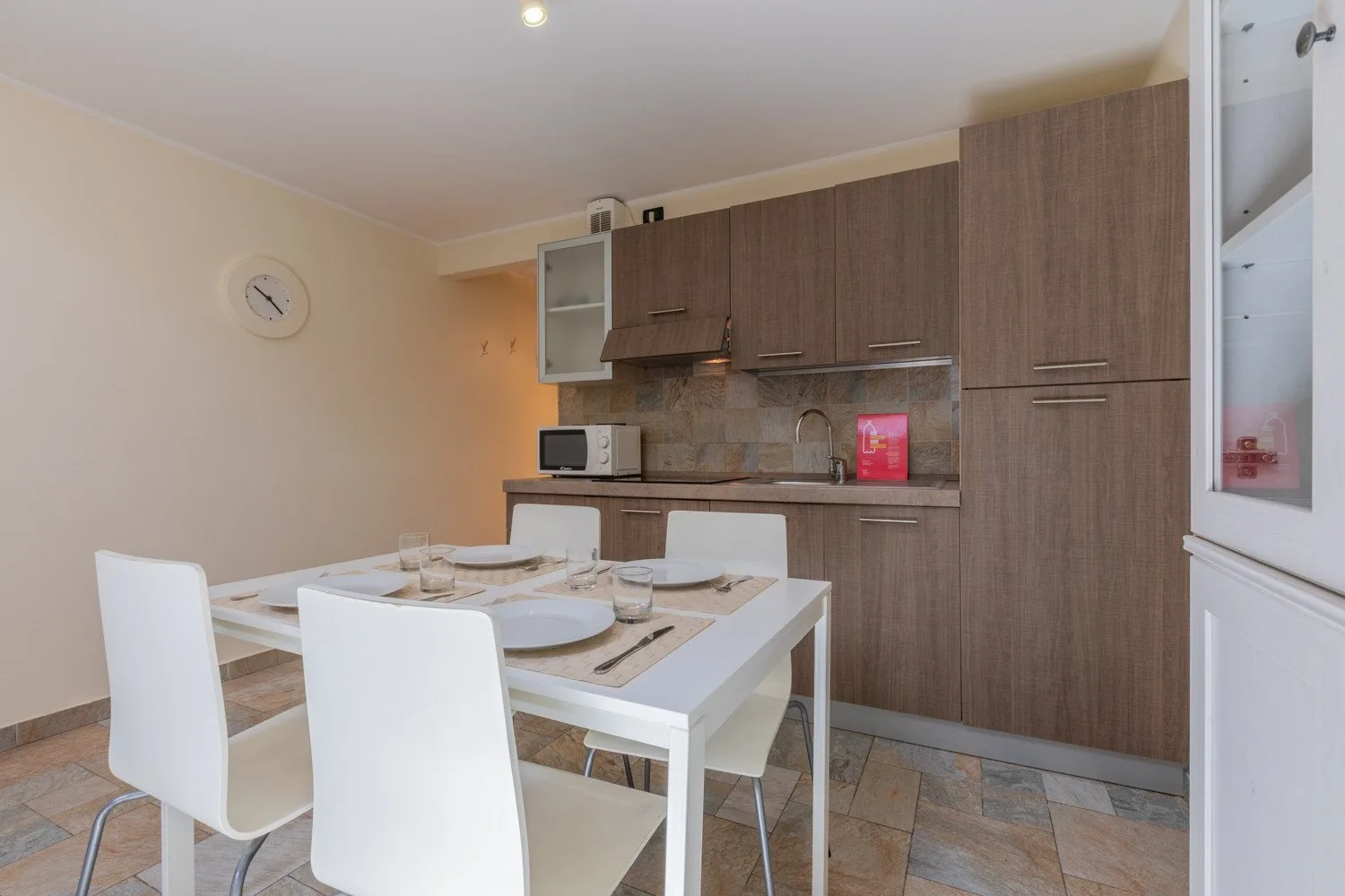 Comedor con la mesa puesta frente a una cocina compacta.
