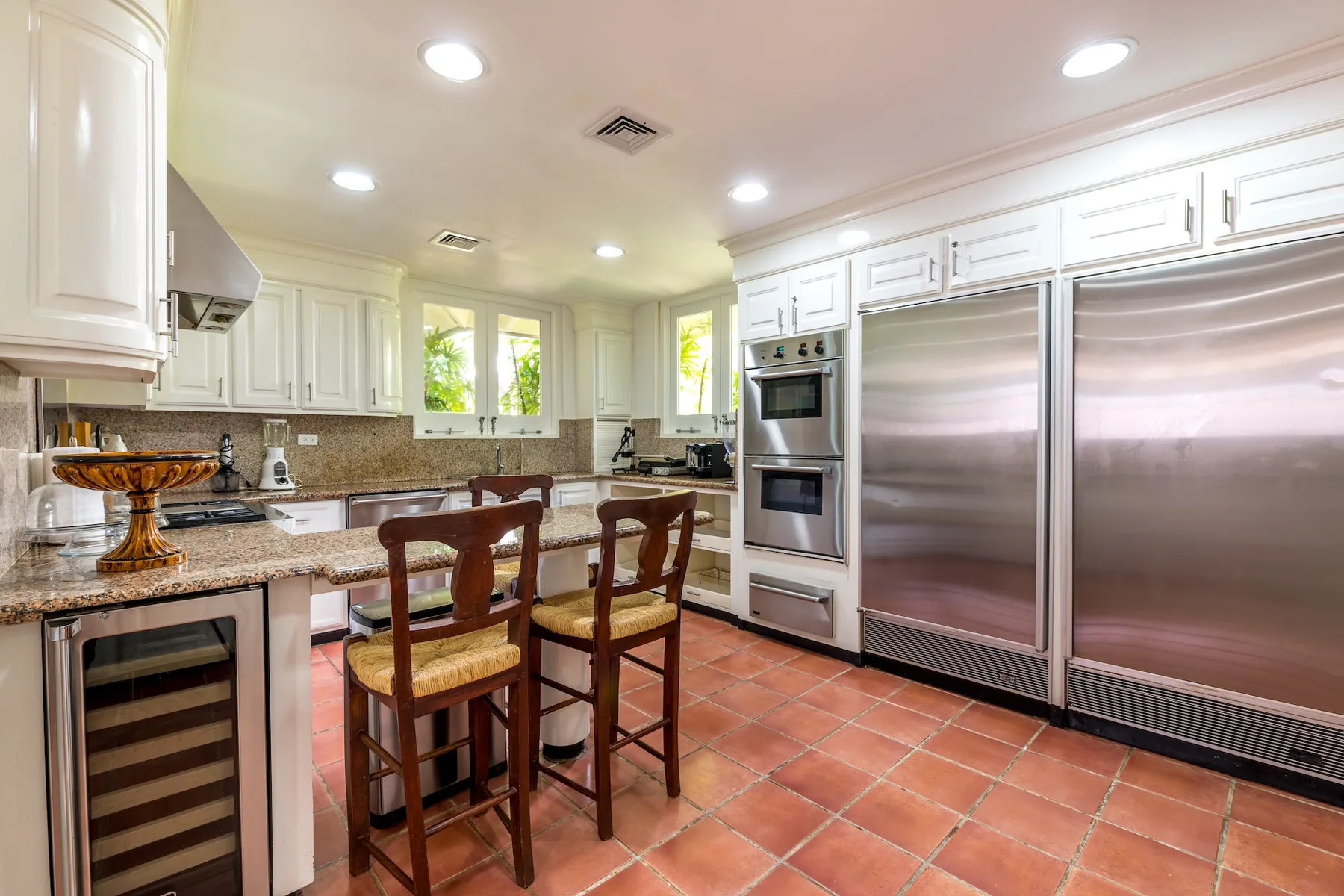 A spacious kitchen with white cabinets, stainless steel appliances, and a tiled floor.